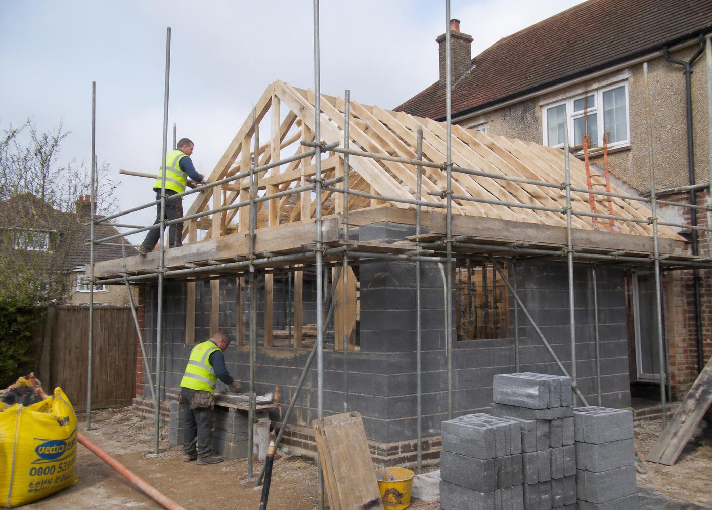 New house extension under construction with scaffolding and timber roof structure